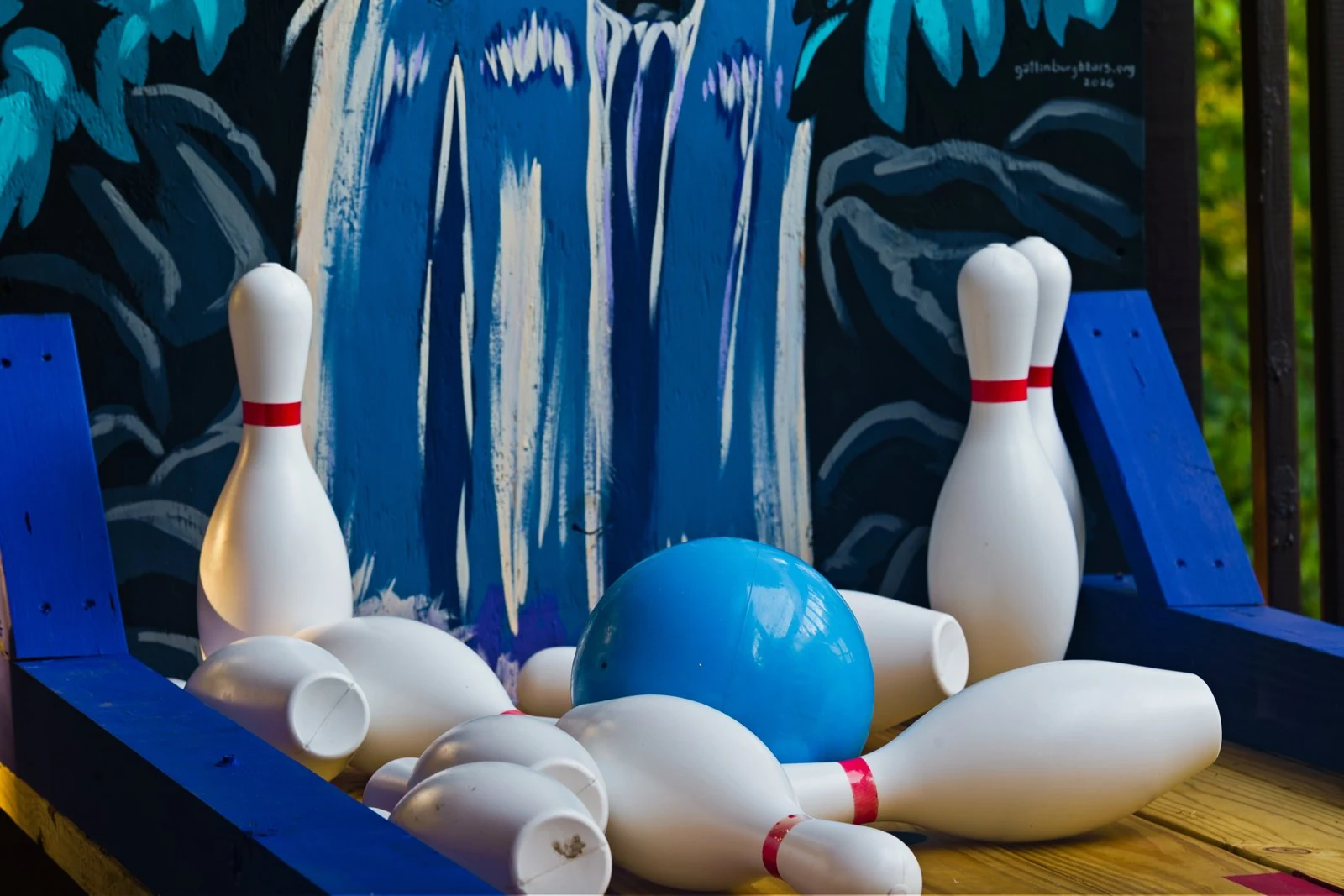 Blue bowling ball and knocked-down pins on the deck bowling lane